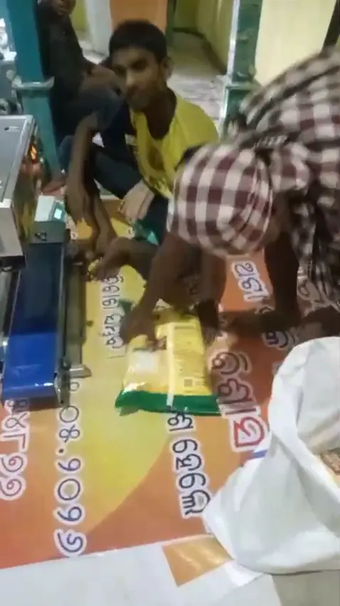 Workers packing and sealing atta packs at the band sealer
